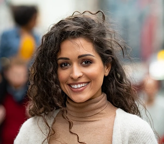 Smiling woman with curly hair on a busy city street